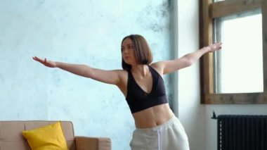 Beyazlı esmer kadın koltuğun yanında yoga yapıyor utthita trikonasana.