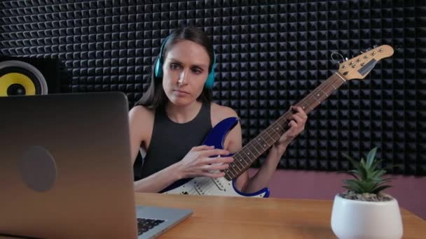 Vrouwelijk leren gitaar spelen thuis met behulp van online lessen. Hobby op afstand muzikaal onderwijs electro gitaar. — Stockvideo