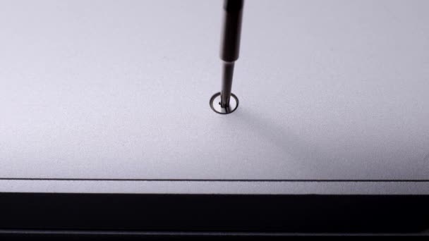 Мастер откручивает маленький винт магнитной отверткой от сломанного ноутбука. — стоковое видео