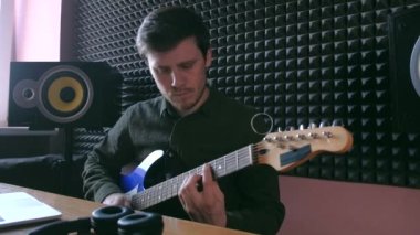 Erkek, online dersleri kullanarak evde gitar çalmayı öğreniyor. Hobi uzaktan müzik eğitimi elektro gitar.