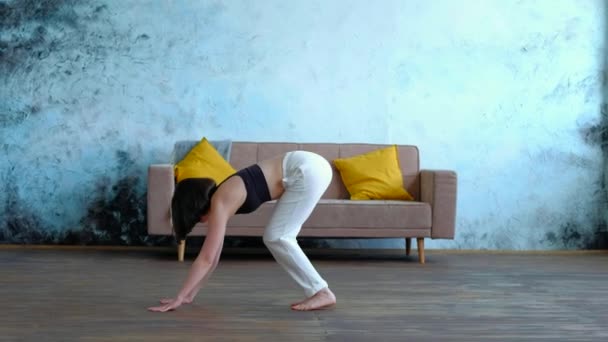 Sevimli esmer kadın kanepe arkasında modern evde yoga egzersizleri yapıyor.. — Stok video