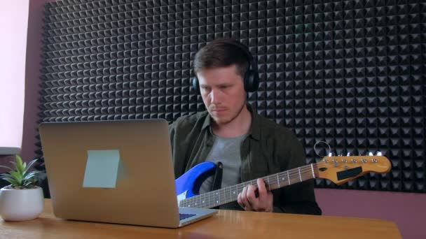 Erkek, online dersleri kullanarak evde gitar çalmayı öğreniyor. Hobi uzaktan müzik eğitimi elektro gitar. — Stok video