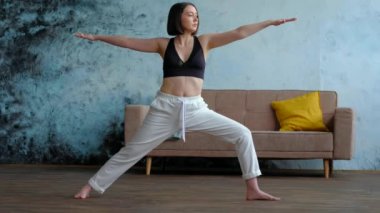 Oturma odasında yoga pozu vermiş bir kadın..