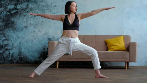 Femeie în camera ei de zi în poziția de yoga războinic . — Videoclip de stoc