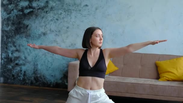 Donna nel suo salotto in posa guerriero yoga. — Video Stock