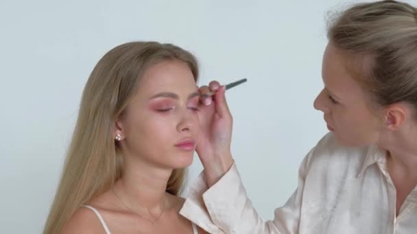 年轻的化妆艺术家向漂亮的模特做化妆 — 图库视频影像