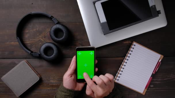 Kädet mies käyttää älypuhelinta, jossa on vihreä näyttö puupöydällä. — kuvapankkivideo