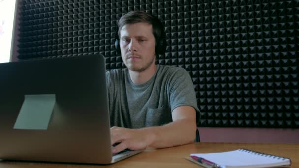 Muž poslouchat hudbu na sluchátka používat notebook v hudební místnosti. — Stock video