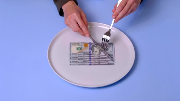 Le mani cercano di mangiare una banconota da un dollaro sul piatto, usando posate, video 4k — Video Stock