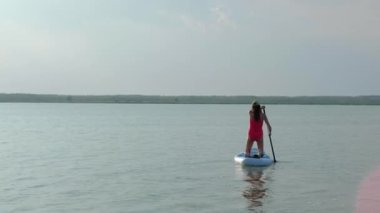 Genç bayan gün batımında sörf yapıyor..
