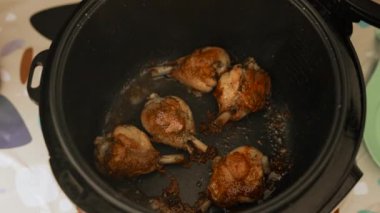 Yavaş pişirilen bir tencerede tavuk budu pişirmek. Bir el kapağı kaldırır, sonra maşa ile kahverengi eti çevirir. Yüksek kalite 4k görüntü