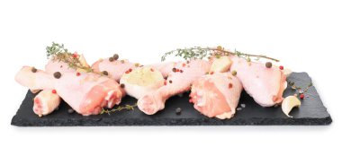 Siyah tahta üzerinde çiğ tavuk budu kekik, sarımsak ve beyaz arka planda izole edilmiş karabiber. Yüksek kalite fotoğraf