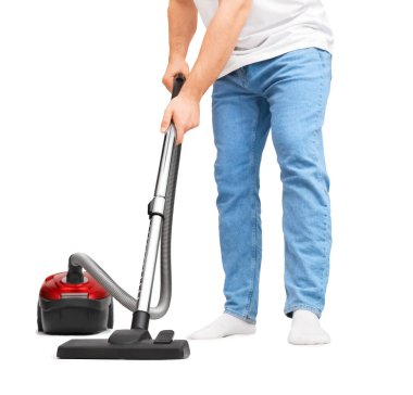 Elektrikli süpürgeyle yerleri temizleyen adam görüntüsü. Mavi kotlu genç adam beyaz arka planda kırmızı ev aletleriyle ev işi yapıyor. Yüksek kalite fotoğraf