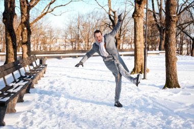 Adam dengesini kaybediyor ve karlı bir parkta buzlu bir yolda kayıyor. Kış kazası konsepti düşme riskini, kaygan ayakkabıları ve açık havada yaralanma tehlikesini gösteriyor. Yüksek kalite fotoğraf