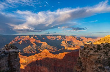 Uçsuz bucaksız Büyük Kanyon manzarasının geniş, yatay manzarası dramatik, kabarık beyaz bulutlarla dolu açık mavi bir gökyüzü altında. Turizm, coğrafi ve vahşi doğa kavramları için harika..