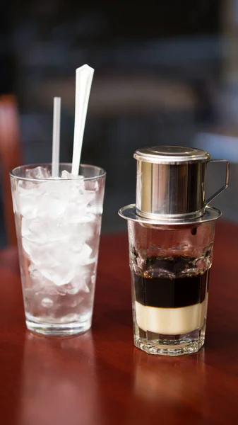 Keskin, dikey bir çekim stüdyosu geleneksel Vietnam buzlu kahvesi yapma sürecini yakalıyor. Koyu sıvı, phin filtresinden yavaş yavaş bir şekilde yoğun süt ve buz bardağına damlıyor..