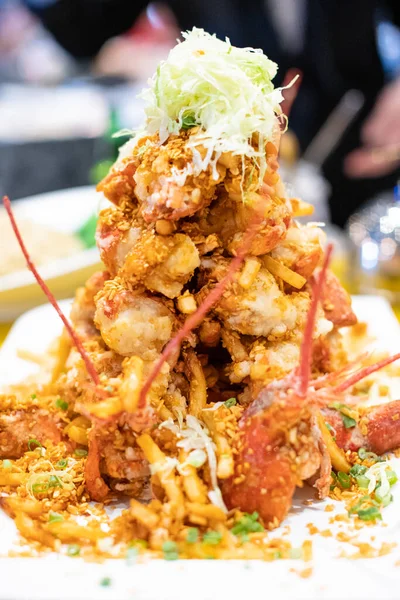 Beyaz bir tabakta taze garnitürle servis edilen altın, çıtır tuz ve biberli ıstakoz parçalarından oluşan bir makro stüdyo. Gurme, Asya mutfağı ve lezzetli yemek kavramları için ideal..