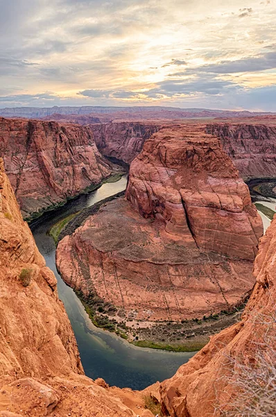Dikey bir görüntü Horseshoe Bend 'in derin kanyonlarını yakalıyor. Günün ilk ışığı kırmızı kaya duvarlarını aydınlatıyor..