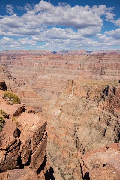 Büyük Kanyon 'un aşırı derinliğini ve tehlikeli sınırlarını yansıtan çarpıcı bir dikey görüntü parlak güneş ışığı altında katmanlı kaya oluşumlarını vurguluyor. Macera ve jeolojik temalar için ideal.
