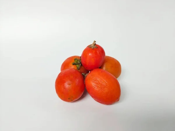 Beyaz arka plana yerleştirilmiş taze kırmızı domatesler doğal dokularını ve basit organik görünüşlerini sergiliyorlar.