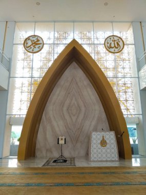LAMPUNG, INDONESIA - 22 Eylül 2025: 22 Eylül 2025 tarihinde Endonezya 'da modern ve sanatsal bir mihrab tasarımının yer aldığı bir cami namaz alanının zarif iç mekanını göstermektedir..