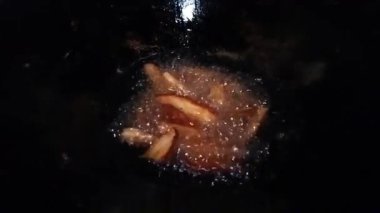 Dilimlenmiş sarımsağın, koyu bir tavanın içinde kızgın yağda kızardığı yakın plan..