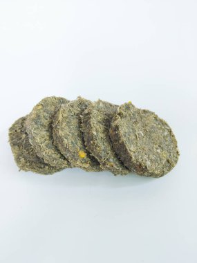 Doğal ot ve bitki malzemelerinden üretilen ve temiz beyaz bir arkaplan üzerine yerleştirilen bir yığın kurumuş hayvan yemi topağının yakın çekimi.