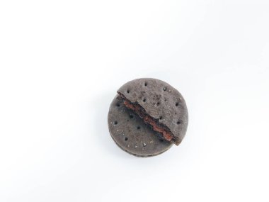 Kırık çikolatalı sandviç kurabiyesinin temiz beyaz arka planda kırmızı krema ile yakın plan görüntüsü.