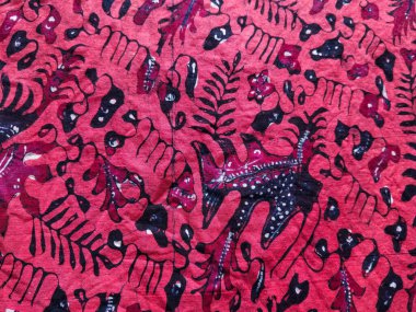 Soyut çiçek ve yaprak motifleri içeren geleneksel kırmızı batik kumaş koyu siyah beyaz aksanlı, Endonezya tekstil sanatını sergiliyor.