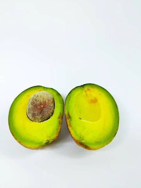 Temiz beyaz bir arkaplana yerleştirilmiş yarım olgun avokado yakın plan.