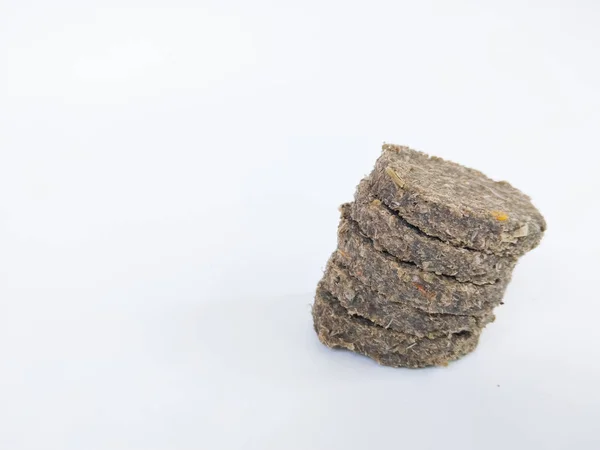 Doğal ot ve bitki malzemelerinden üretilen ve temiz beyaz bir arkaplan üzerine yerleştirilen bir yığın kurumuş hayvan yemi topağının yakın çekimi.