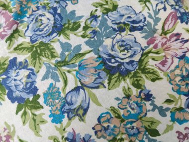 Beyaz arka planda yeşil yapraklı mavi, mor ve pembe çiçeklerden oluşan renkli bir kumaş deseni.