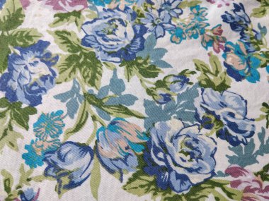 Beyaz arka planda yeşil yapraklı mavi, mor ve pembe çiçeklerden oluşan renkli bir kumaş deseni.