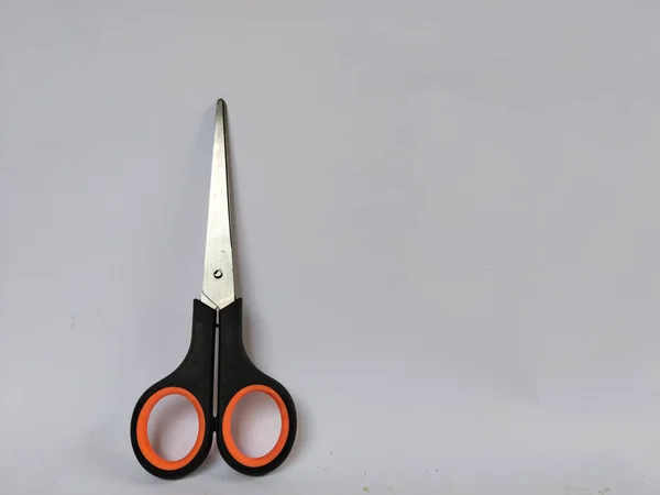 Siyah saplı, turuncu iç saplı, düz beyaz bir arka plana yerleştirilmiş bir makas çifti.