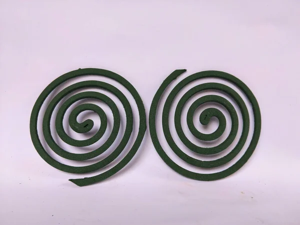 Sade beyaz bir arkaplana yerleştirilmiş spiral şeklinde yeşil bir sivrisinek bobini..