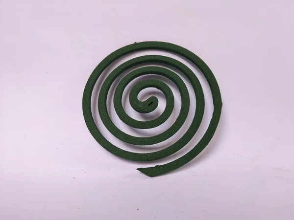 Sade beyaz bir arkaplana yerleştirilmiş spiral şeklinde yeşil bir sivrisinek bobini..