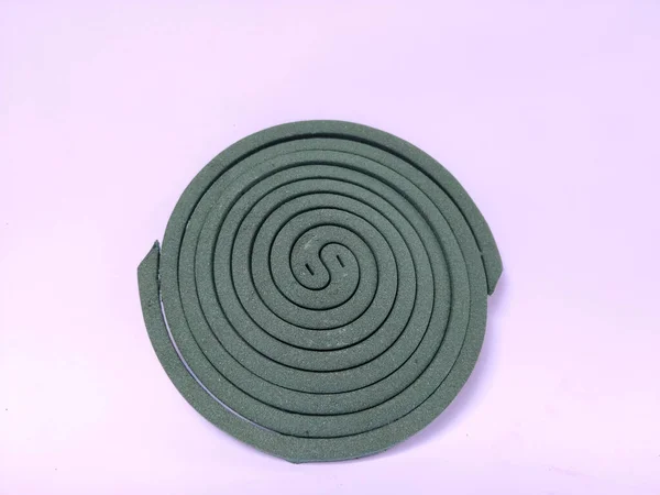 Sade beyaz bir arkaplana yerleştirilmiş spiral şeklinde yeşil bir sivrisinek bobini..