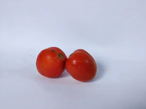 Beyaz arka plana yerleştirilmiş taze kırmızı domatesler doğal dokularını ve basit organik görünüşlerini sergiliyorlar.