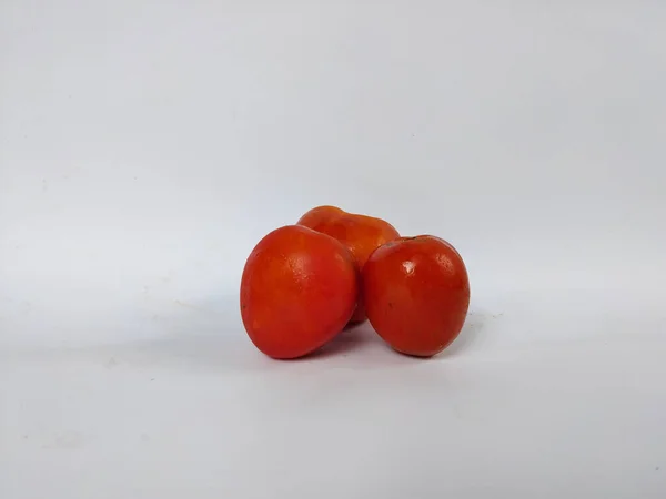 Beyaz arka plana yerleştirilmiş taze kırmızı domatesler doğal dokularını ve basit organik görünüşlerini sergiliyorlar.