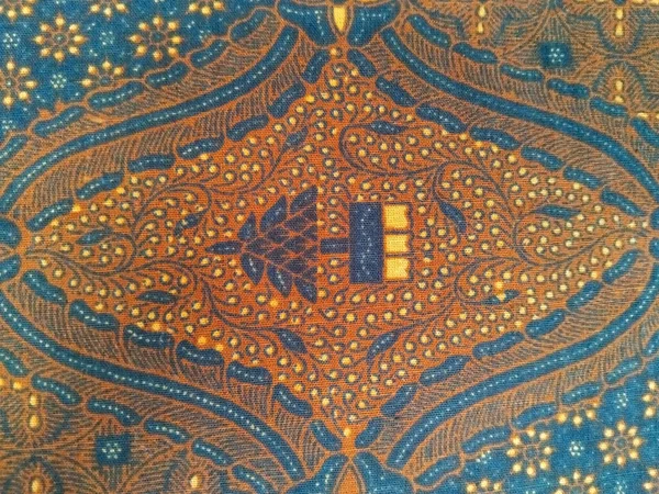 Karmaşık kahverengi, mavi ve sarı desenli geleneksel batik kumaş, simetrik dizaynlı çiçekli ve geometrik motifler.