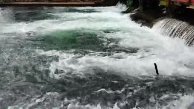 Nehir suyunun akışını yakından görmek dinamik dalgalanmalar yaratır ve karanlık kayaların üzerinde hareket ederken su sıçratır.
