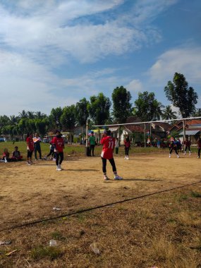 LAMPUNG, INDONESIA - 03 Ağustos 2025: Güneşli bir günde kızlar voleybol oynuyor, seyirciler ve hakem izliyor, Endonezya, 3 Ağustos 2025.