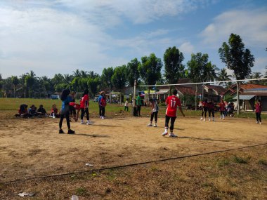 LAMPUNG, INDONESIA - 03 Ağustos 2025: Güneşli bir günde kızlar voleybol oynuyor, seyirciler ve hakem izliyor, Endonezya, 3 Ağustos 2025.
