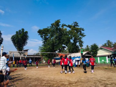 LAMPUNG, INDONESIA - 03 Ağustos 2025: Güneşli bir günde kızlar voleybol oynuyor, seyirciler ve hakem izliyor, Endonezya, 3 Ağustos 2025.
