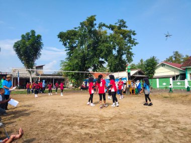 LAMPUNG, INDONESIA - 03 Ağustos 2025: Güneşli bir günde kızlar voleybol oynuyor, seyirciler ve hakem izliyor, Endonezya, 3 Ağustos 2025.