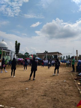 LAMPUNG, INDONESIA - 03 Ağustos 2025: Güneşli bir günde kızlar voleybol oynuyor, seyirciler ve hakem izliyor, Endonezya, 3 Ağustos 2025.
