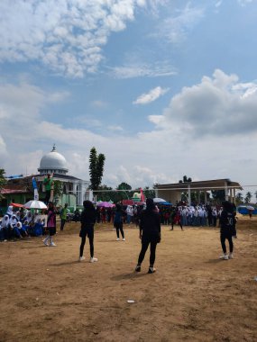 LAMPUNG, INDONESIA - 03 Ağustos 2025: Güneşli bir günde kızlar voleybol oynuyor, seyirciler ve hakem izliyor, Endonezya, 3 Ağustos 2025.