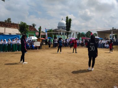 LAMPUNG, INDONESIA - 03 Ağustos 2025: Güneşli bir günde kızlar voleybol oynuyor, seyirciler ve hakem izliyor, Endonezya, 3 Ağustos 2025.