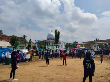 LAMPUNG, INDONESIA - 03 Ağustos 2025: Güneşli bir günde kızlar voleybol oynuyor, seyirciler ve hakem izliyor, Endonezya, 3 Ağustos 2025.