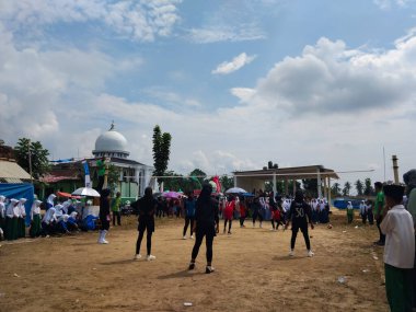 LAMPUNG, INDONESIA - 03 Ağustos 2025: Güneşli bir günde kızlar voleybol oynuyor, seyirciler ve hakem izliyor, Endonezya, 3 Ağustos 2025.